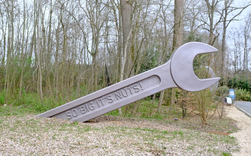 image of a giant spanner; the size of a tree, lying half embedded in the ground, with the other half in the air