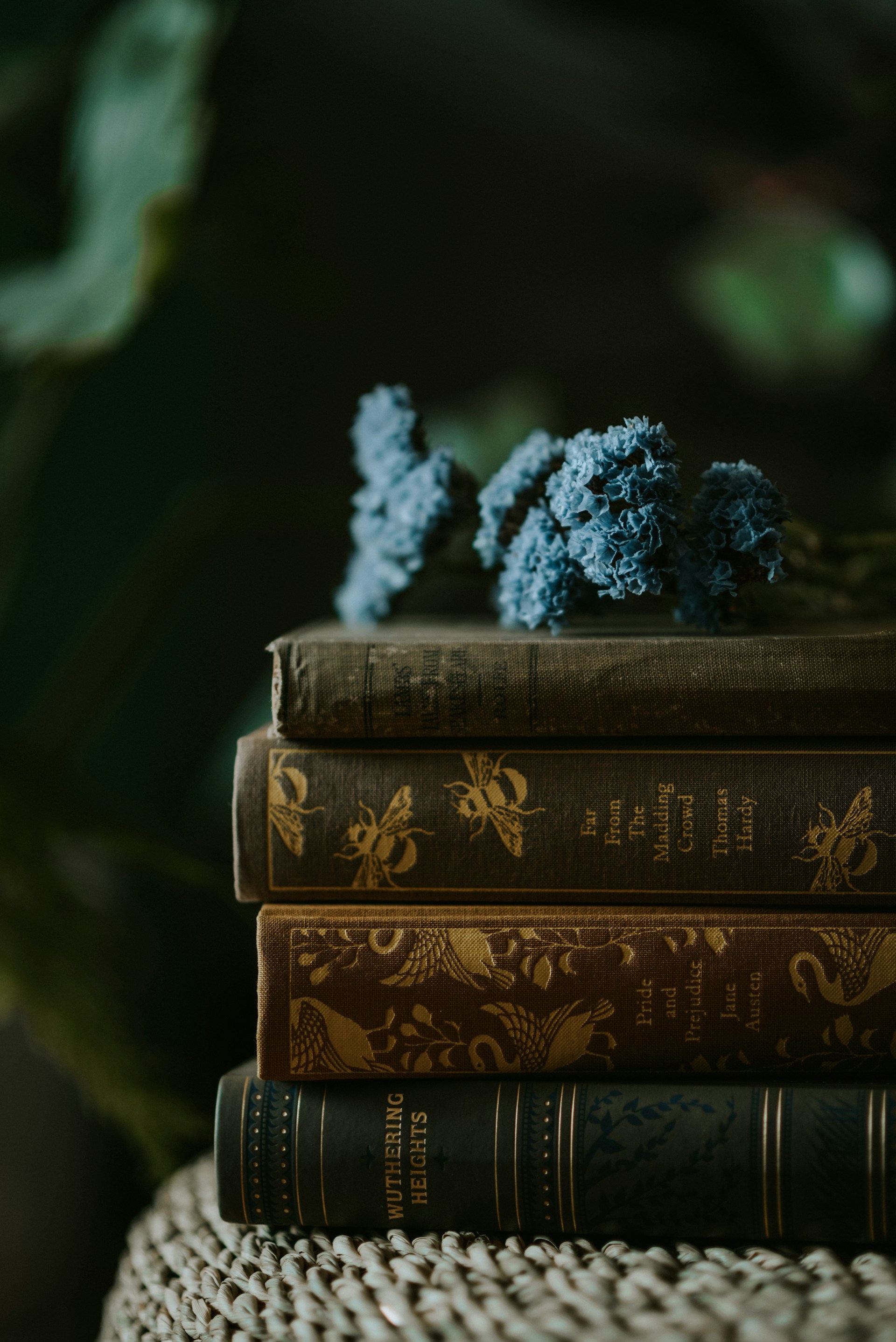 pile of old english classic books with a flower on top